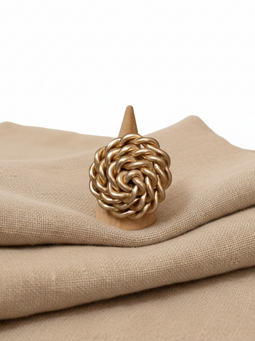  "Anello spirale dorato maxi vista frontale su porta anello in legno su tessuto lino naturale"