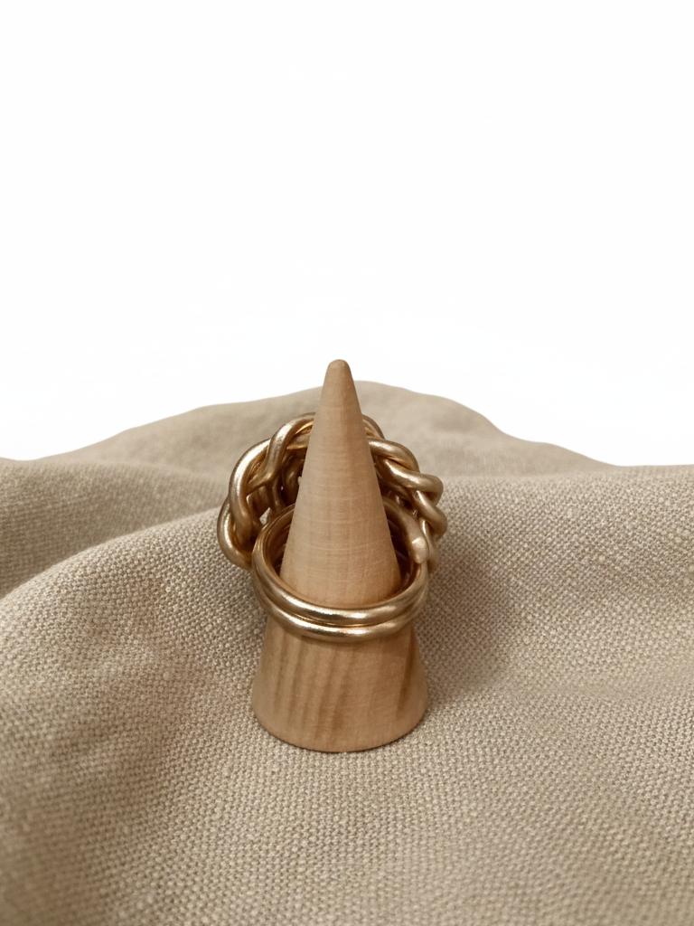  "Anello spirale dorato maxi vista laterale dettaglio intreccio su porta anello in legno tessuto lino"
