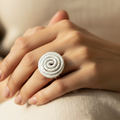  "Anello a spirale in alluminio anodizzato argento indossato su mano femminile sfondo beige stile elegante artigianale"